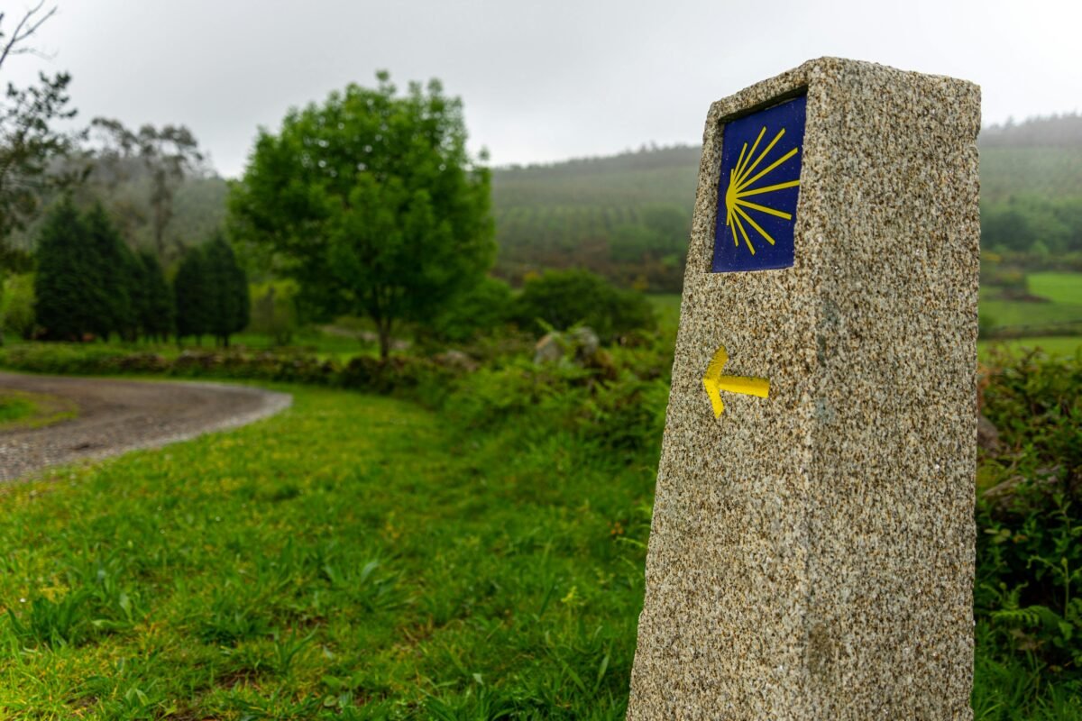 paisaje mojón con flecha amarilla señalando la vía al camino de santiago